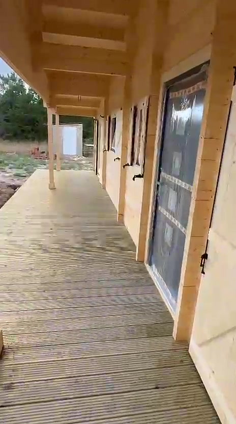 Alpendre de casa de madeira com deck em madeira tratada e portas-janela com portadas