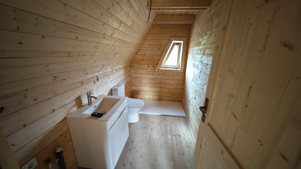 Casa de banho de uma casa A-Frame em madeira com lavatório, sanita e base de duche