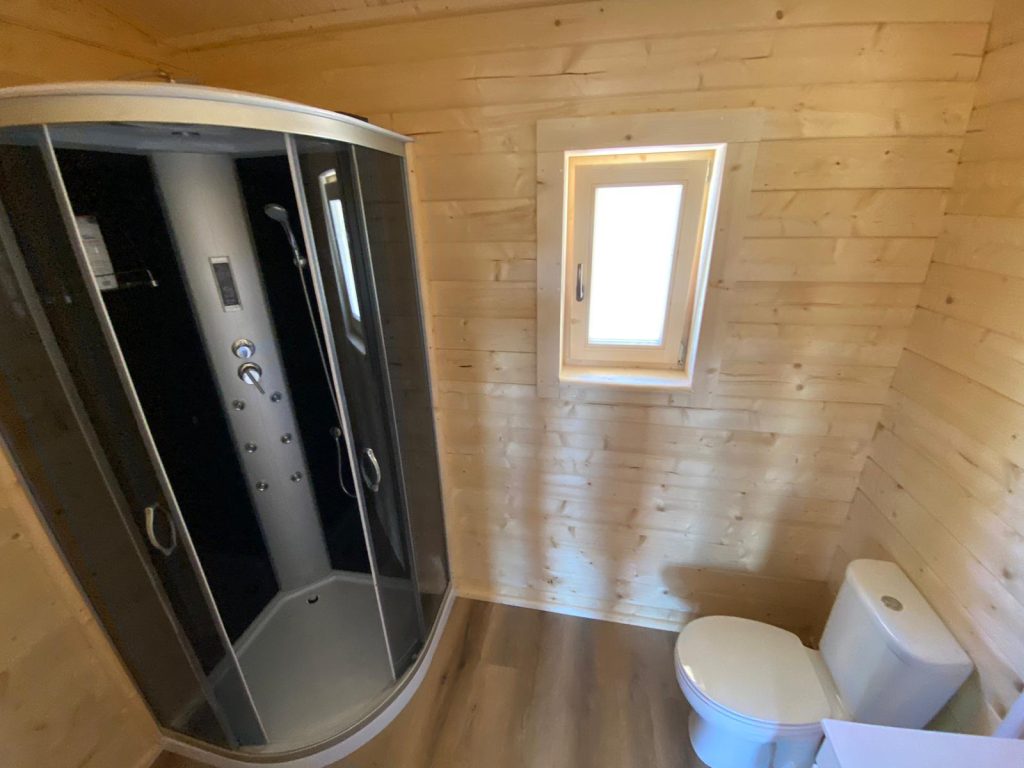 Casa de banho de casa de madeira com cabine de duche com hidromassagem e janela oscilobatente