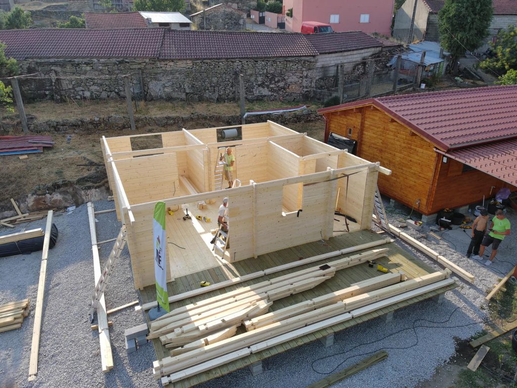 Vista aérea de casa de madeira em montagem com paredes concluídas e alpendre em deck