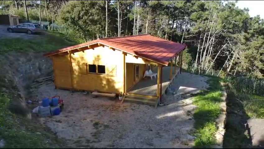 Casa de madeira maciça no meio do pinhal, com alpendre e telhado em telha vermelha