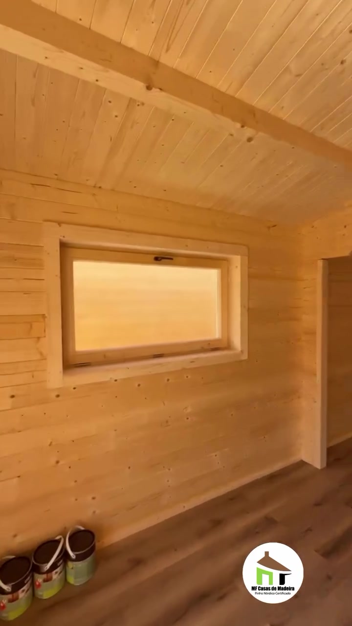 Quarto com teto inclinado em madeira e janela