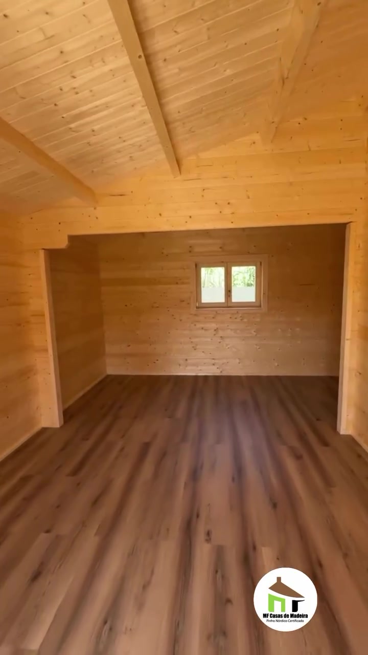Sala com teto inclinado em pinho e vigas de madeira maciça à vista