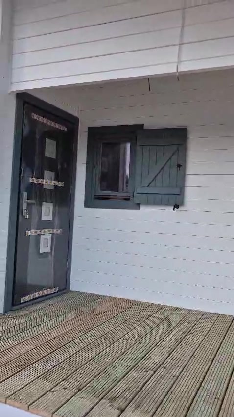 Fachada de casa de madeira branca com portadas cinza