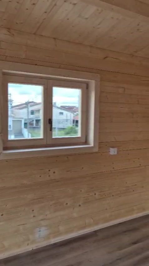 Quarto em casa de madeira MF com janela e paredes de pinho