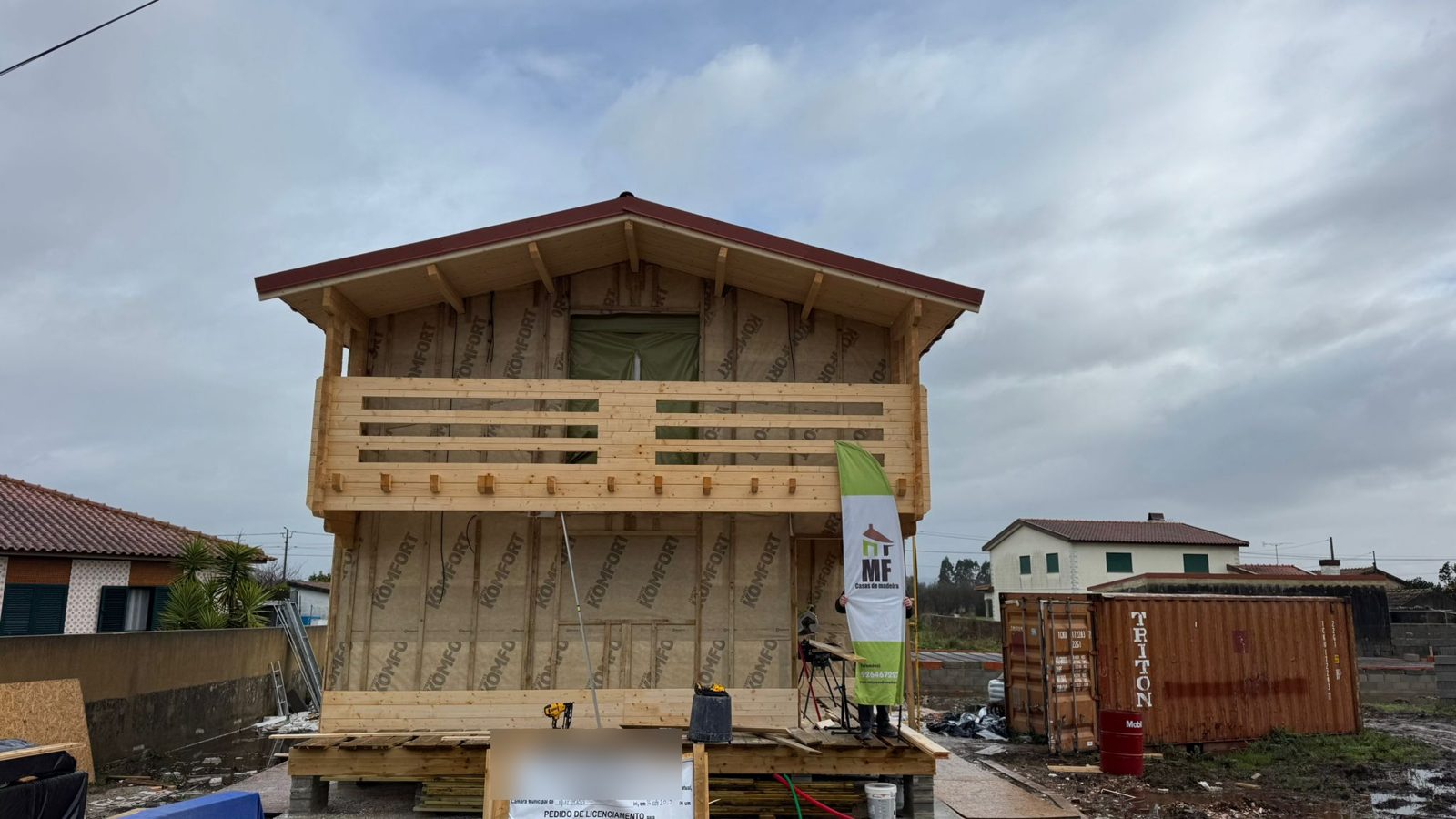 Fachada com membrana exterior e ripado vertical, varanda em madeira e beirais forrados