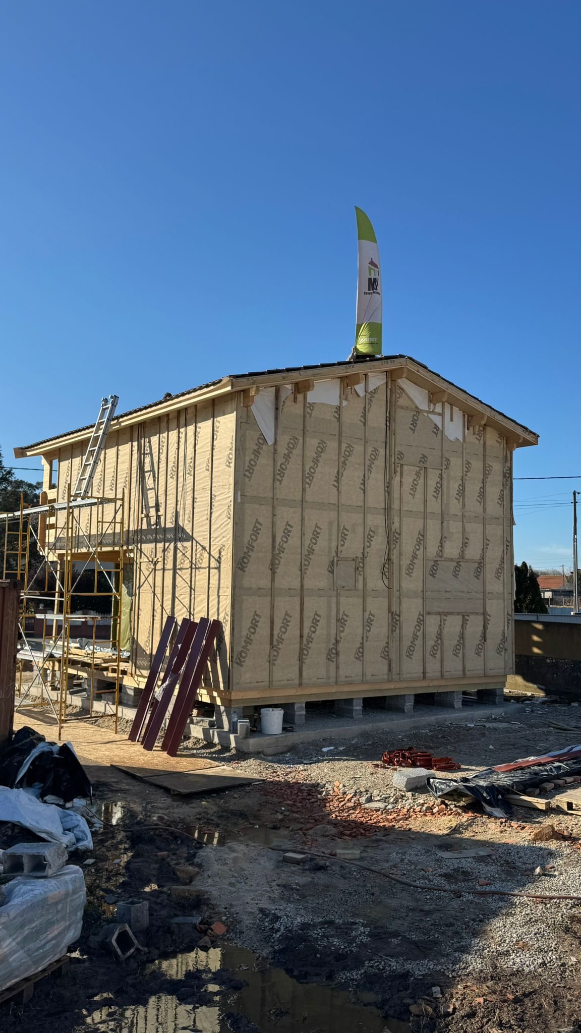 Fachada lateral com membrana exterior e ripado, casa elevada sobre maciços