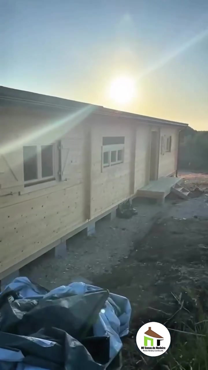 Casa de madeira modelo Dupla T4 ao fim da tarde, elevada acima do terreno