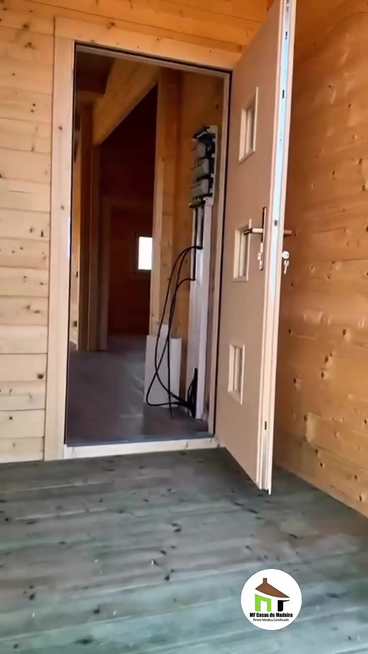 Porta de entrada aberta da casa de madeira Dupla, com vista para o interior
