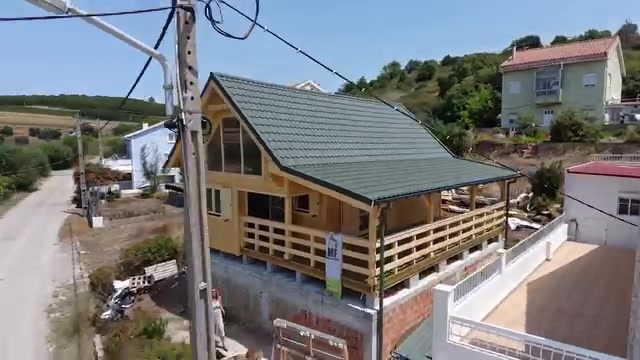 Fachada lateral da casa de madeira Estrela T2 com cobertura em telha verde