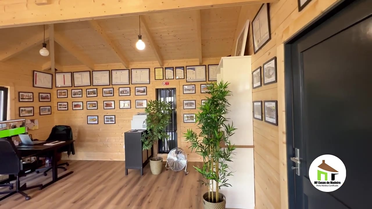 Interior da casa de exposição em pinho nórdico maciço, com teto inclinado à vista e escritório de atendimento MF