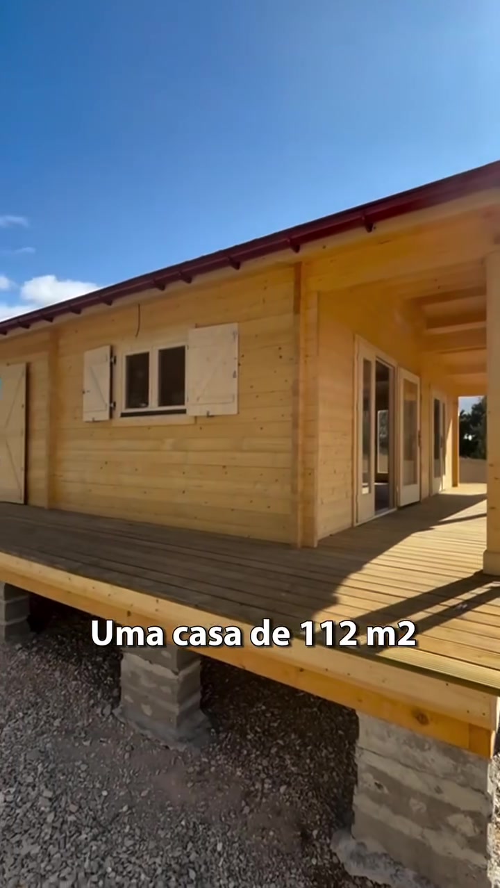 Casa de madeira de 112 m² elevada sobre maciços de betão, com deck em madeira