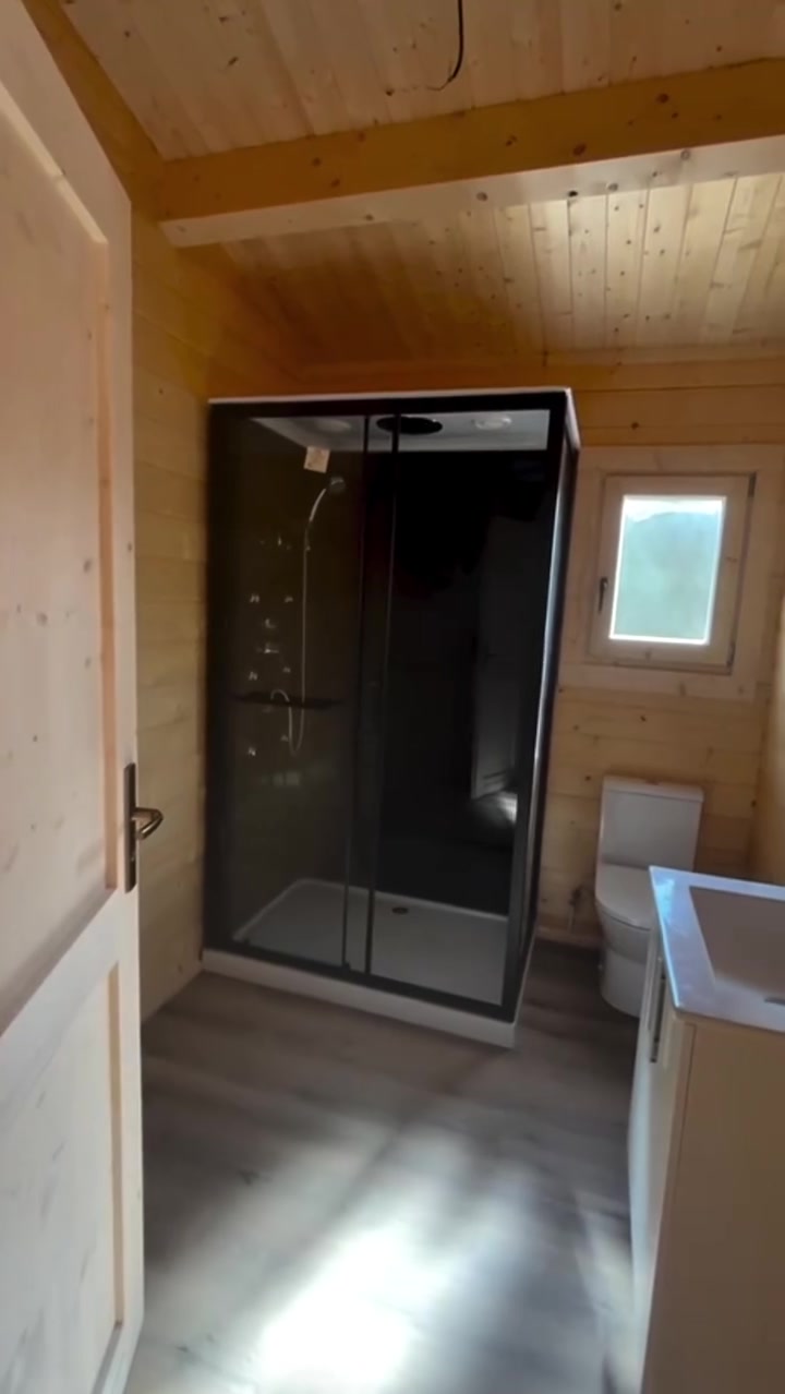 Casa de banho com cabine de duche em vidro numa casa de madeira maciça