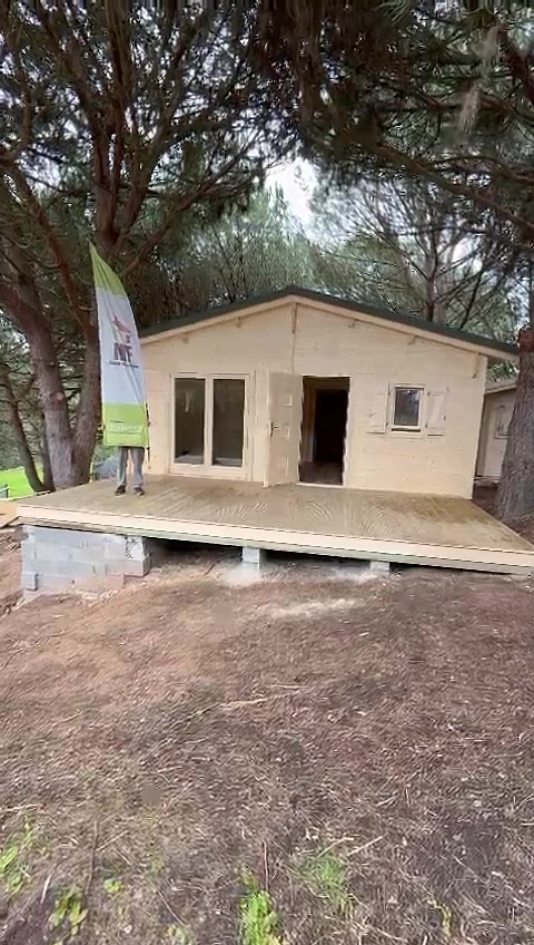 Casa de madeira térrea em pinho maciço num pinhal, com deck em madeira e cobertura verde