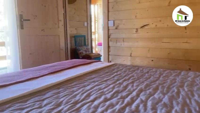 Quarto em casa de madeira maciça com paredes em pinho à vista