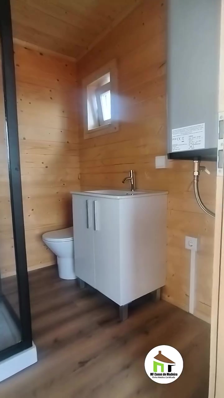 Casa de banho da casa de madeira T0 com móvel de lavatório, sanita e termoacumulador