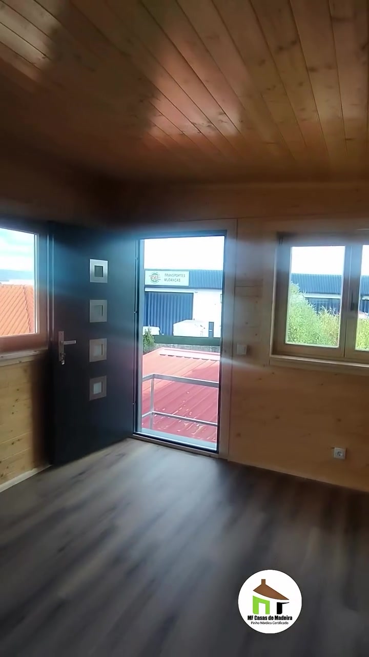 Sala da casa de madeira T0 com porta de entrada e janela
