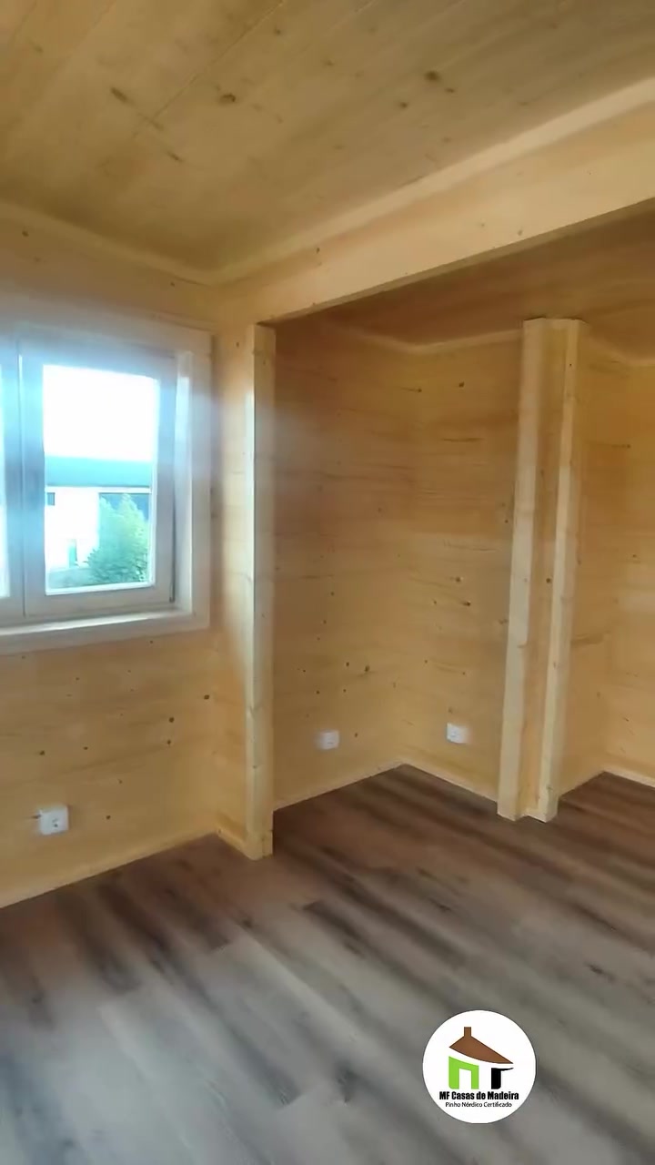 Espaço interior da casa T0 com janela e paredes em madeira maciça