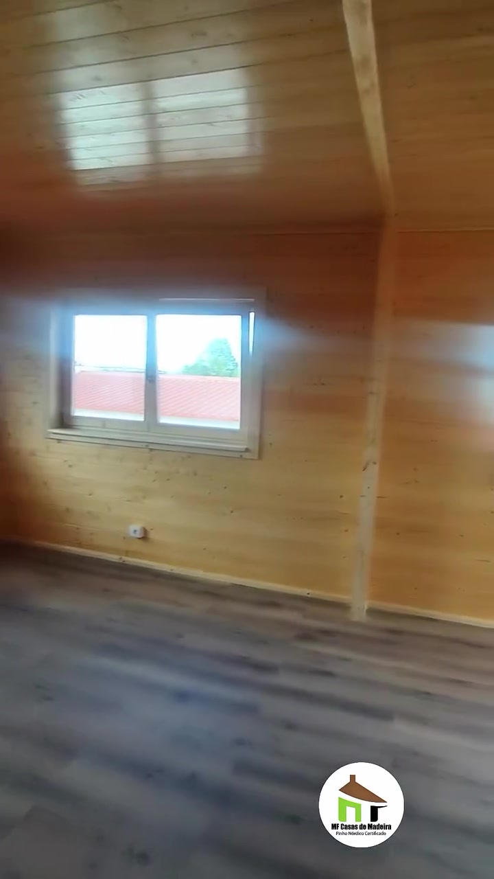 Zona de dormir da casa de madeira T0, com janela e pavimento laminado