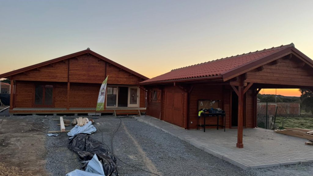 Casa de madeira térrea e garagem em madeira maciça com telheiro, construídas pela MF, ao pôr do sol
