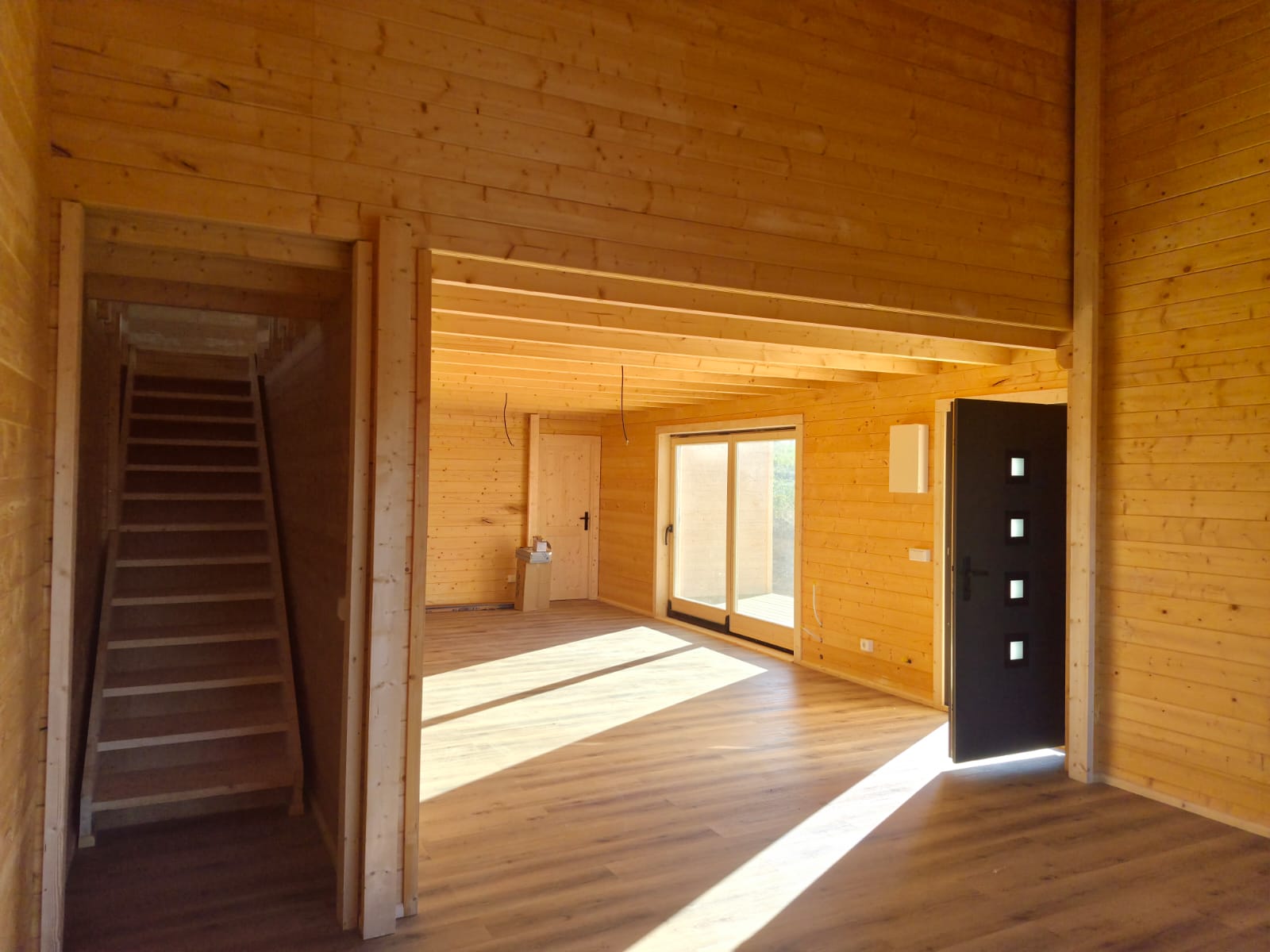 Hall de entrada com escada para o mezanino e sala com teto em vigas de madeira