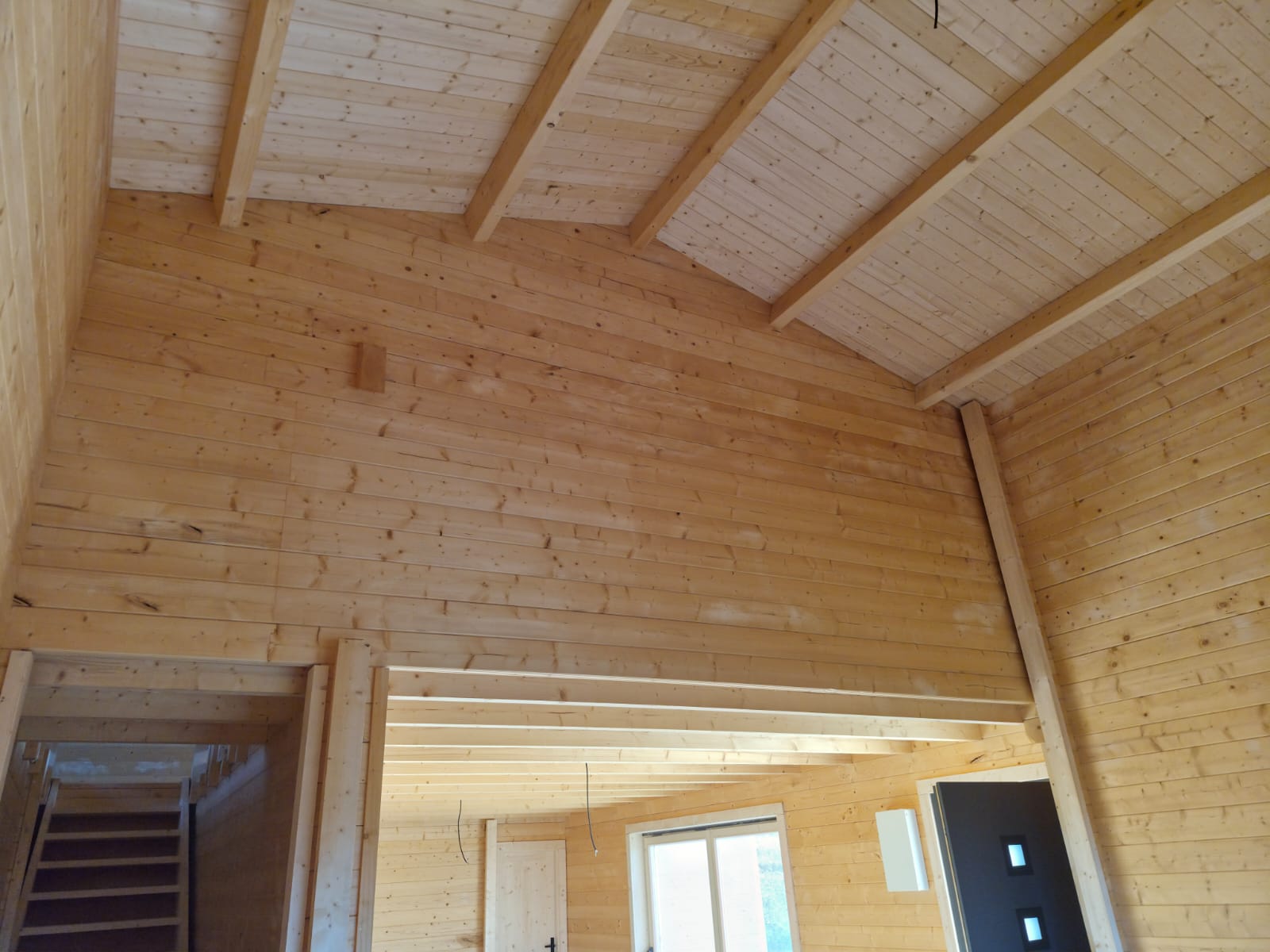 Sala em pé-direito duplo com teto inclinado em pinho maciço e vigas à vista