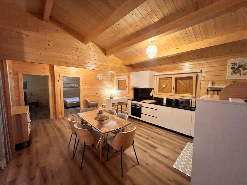 Cozinha, mesa de jantar e acesso aos quartos de uma casa de madeira T2