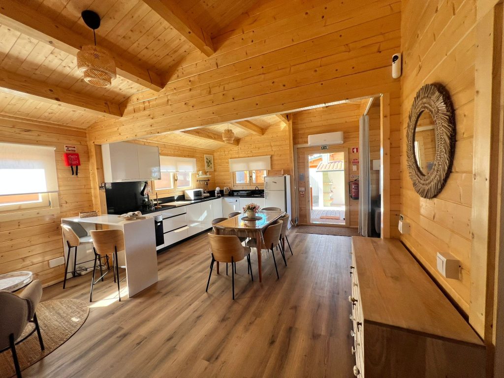 Cozinha e sala de jantar de uma casa de madeira para alojamento local, com vigas de madeira à vista