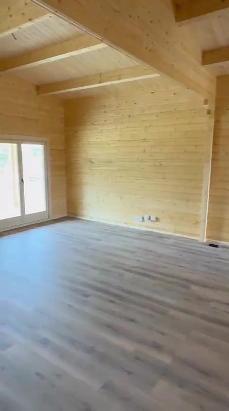 Divisão de casa de madeira maciça com vigas à vista, teto em pinho e janela
