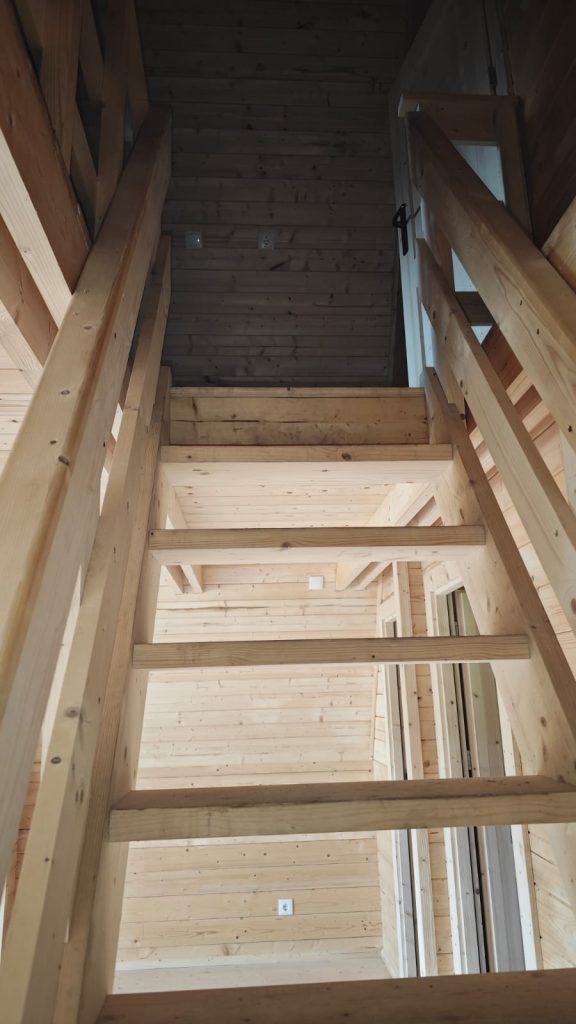 Escada em madeira maciça de acesso ao mezanino de uma casa A-Frame
