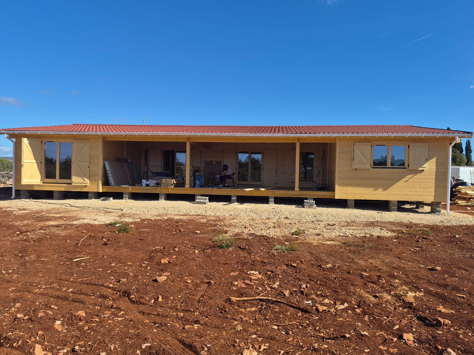 Casa de madeira T3 com telhado de telha cerâmica vermelha e alpendre a toda a frente, construída pela MF Casas de Madeira