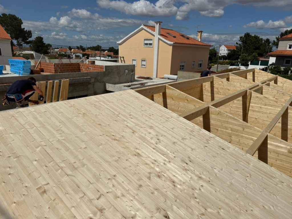 Forro em pinho a fechar a cobertura sobre madres e empenas interiores de uma casa de madeira maciça
