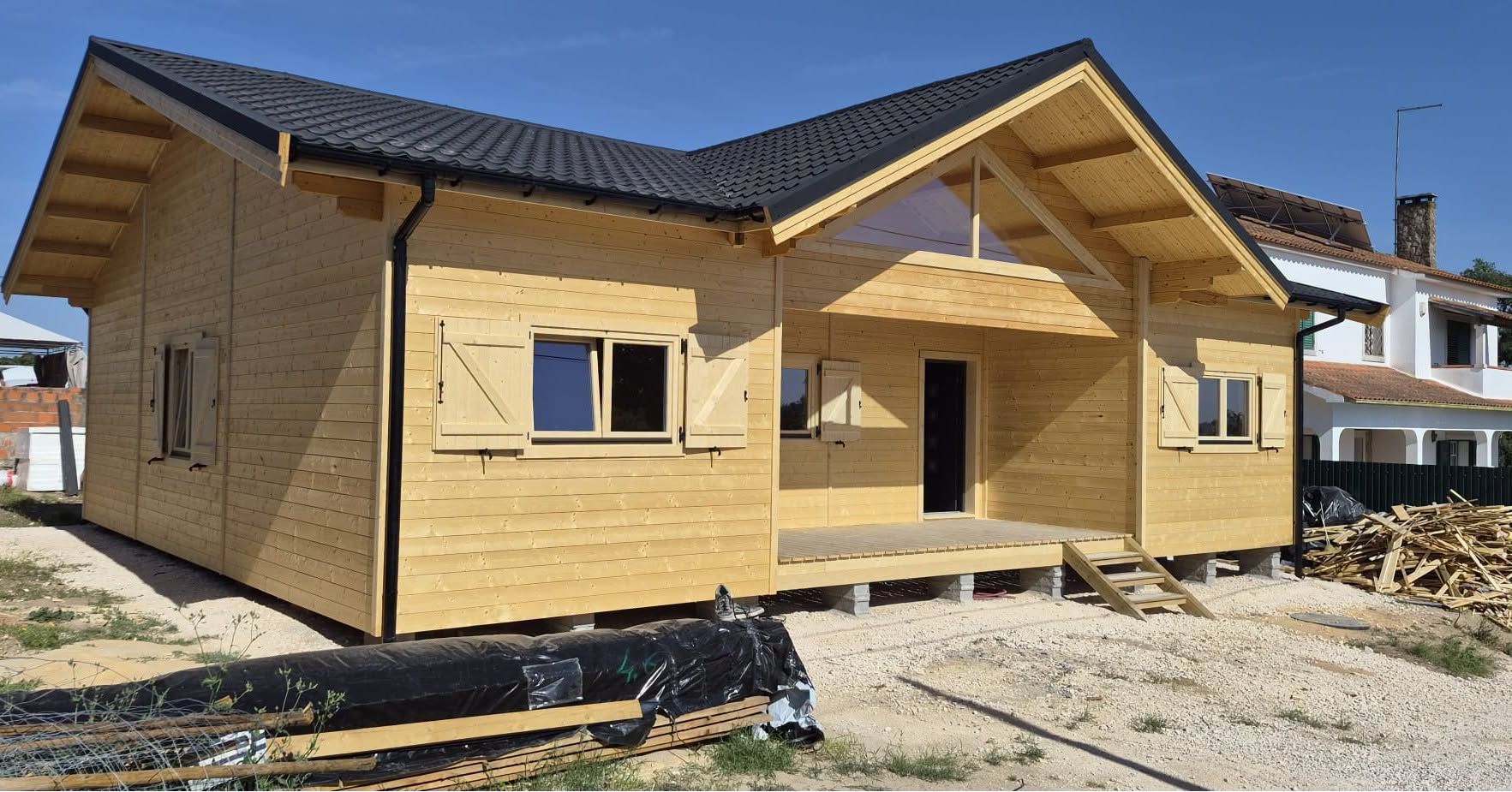 Moradia térrea em madeira construída pela MF Casas de Madeira, com alpendre coberto, frontão envidraçado e cobertura em telha preta