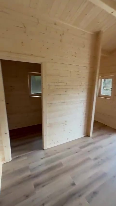 Interior de casa de madeira maciça com aberturas para as divisões e pavimento vinílico