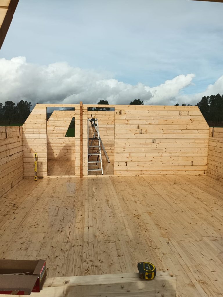 Paredes em toros maciços e pavimento em pinho no rés-do-chão de uma casa A-Frame