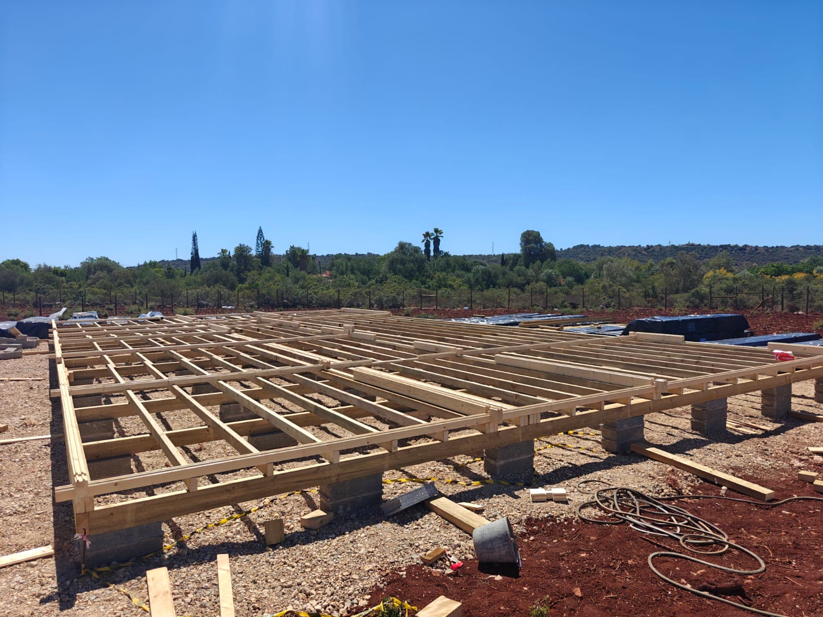 Plataforma de vigas de madeira tratada assente em maciços de betão, base de uma casa de madeira MF