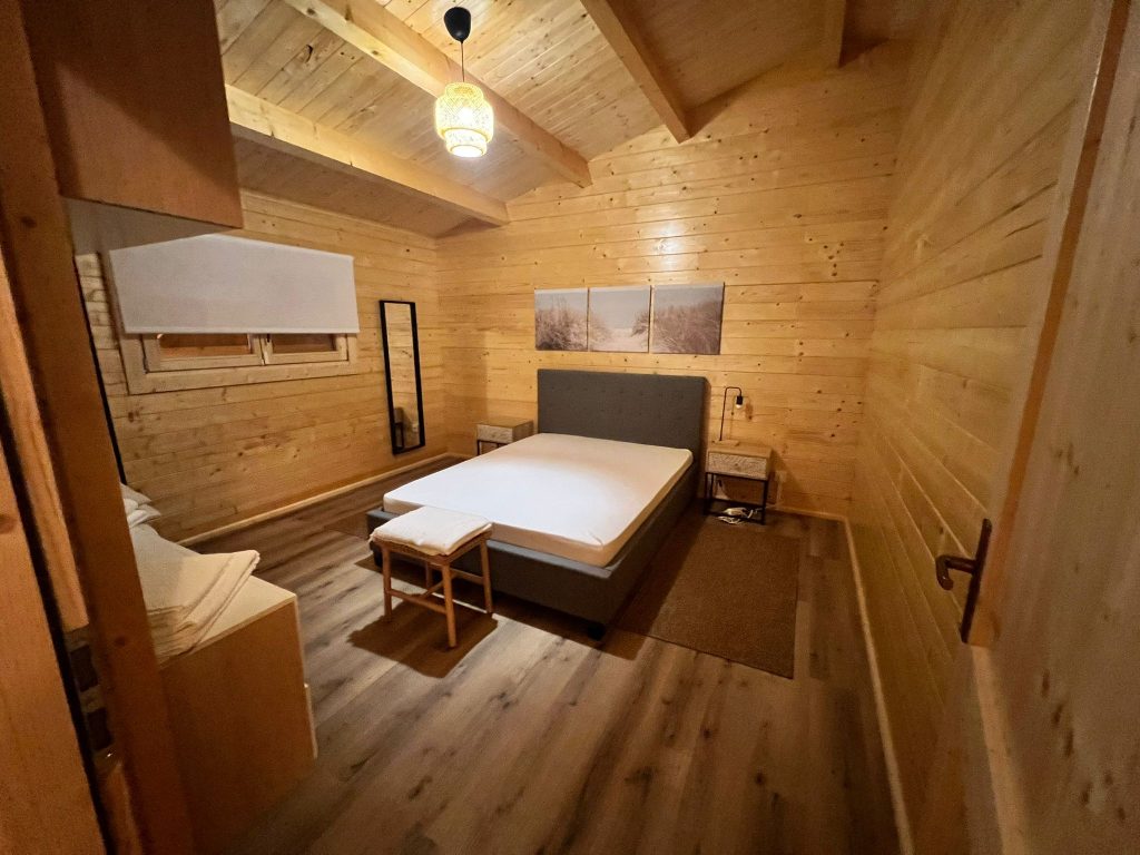 Quarto de casal com paredes e teto em pinho maciço numa casa de madeira