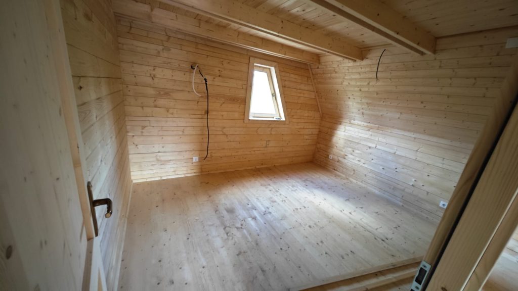 Quarto no mezanino de uma casa A-Frame com paredes, teto e chão em pinho maciço
