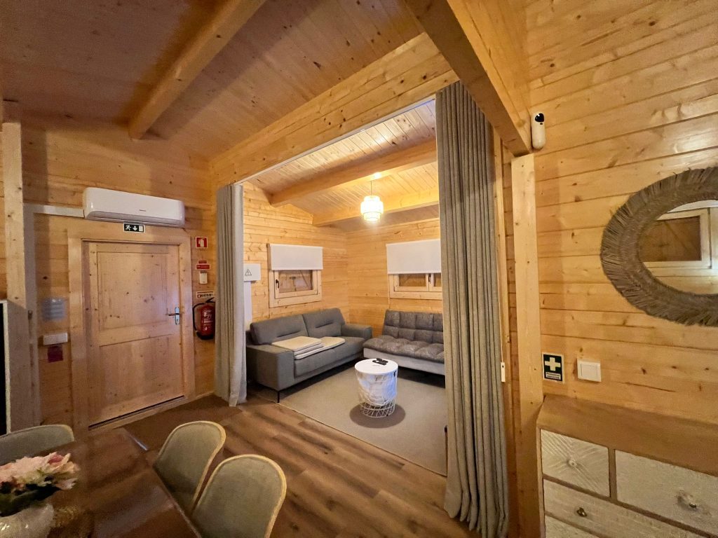 Sala de estar com sofás e cortina divisória numa casa de madeira para alojamento local