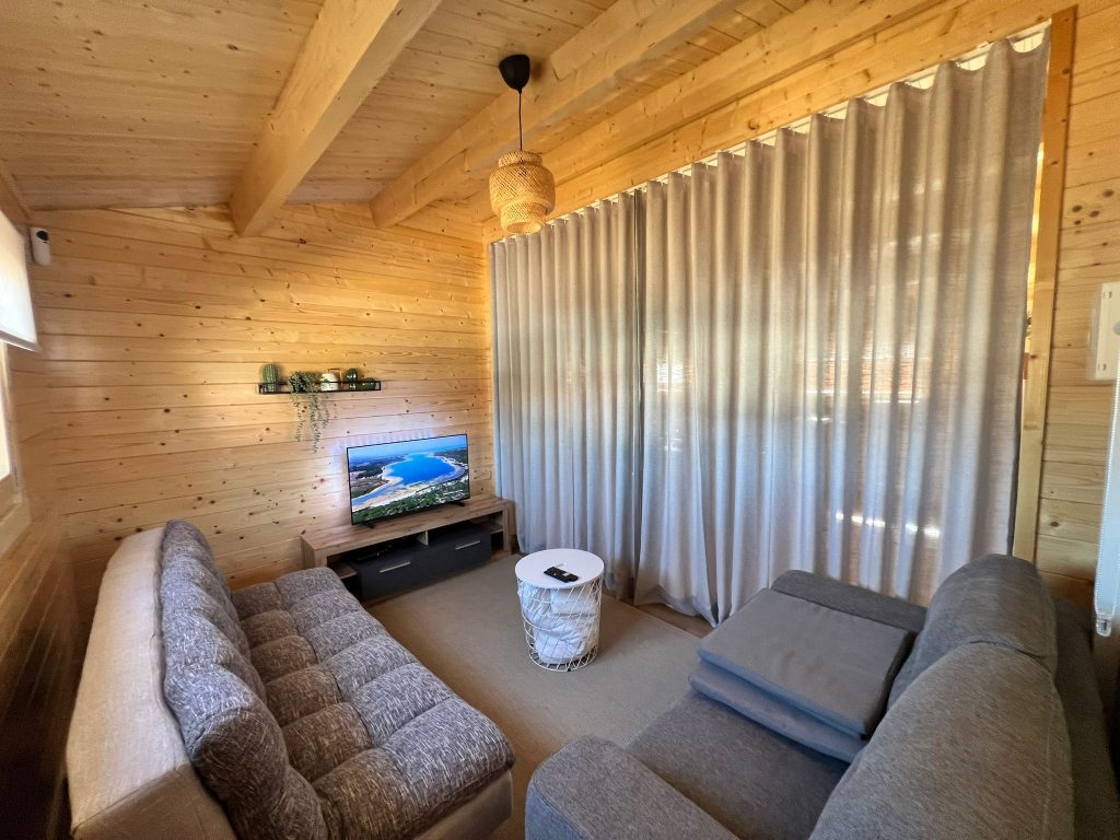 Sala de estar com televisão, sofás e teto em madeira com vigas à vista