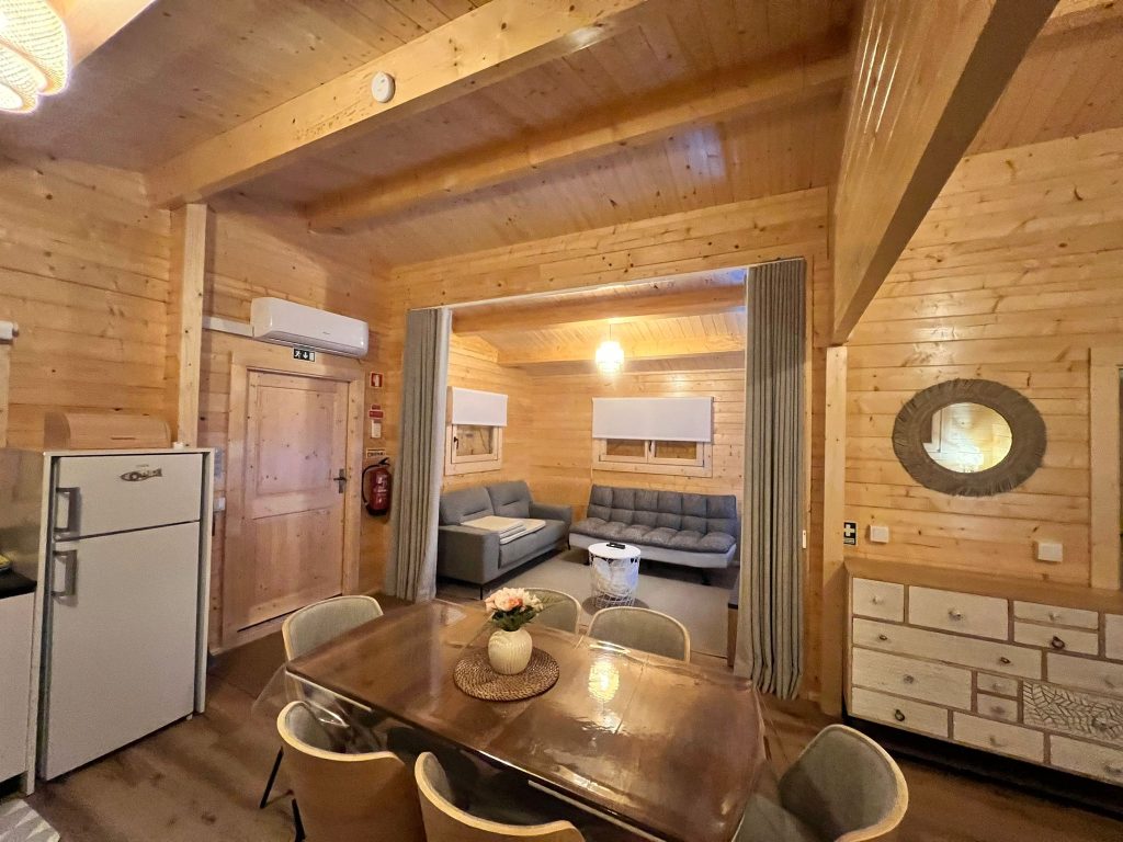 Sala de jantar com vista para a sala de estar separada por cortina numa casa de madeira