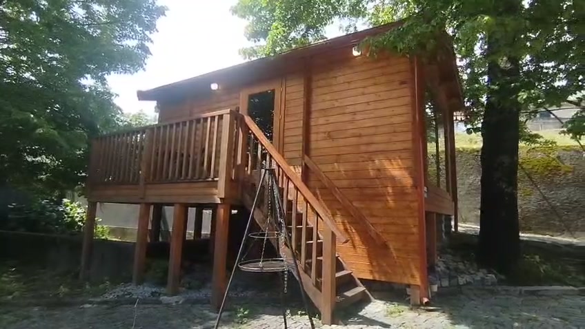 Tiny house na árvore em madeira maciça, elevada sobre pilares, com varanda em deck e escada com guarda, obra MF